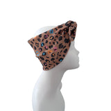 A leopard print headband with a side knot, displayed on a white mannequin head in profile against a solid white background.
