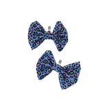 Two purple leopard print bows with clips on a white background