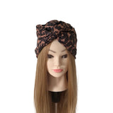 A leopard print hair wrap headband styled on a mannequin head with long light brown hair, set against a plain white background.