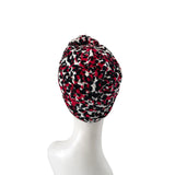 Turban with red and black pattern on a white mannequin head against a white background