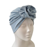 Light blue headscarf with a flower on a mannequin head against a white background