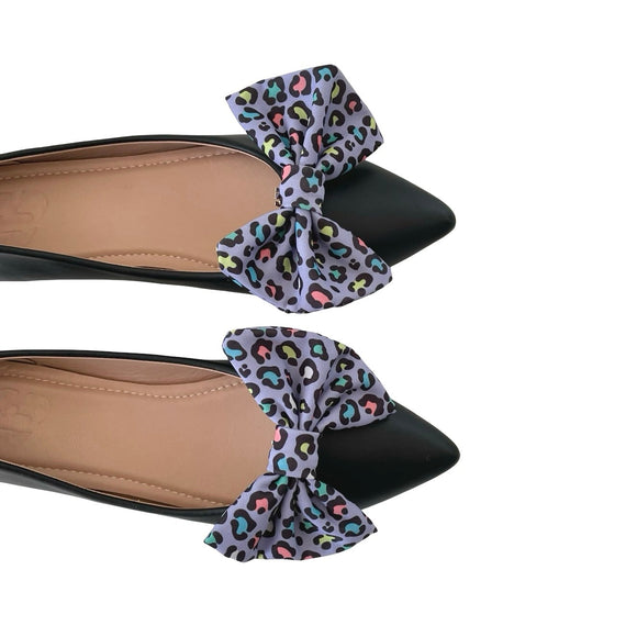Black flats with colorful leopard print bows on a white background