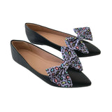 Black pointed-toe flats with colorful leopard print bows on a white background