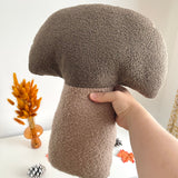 Brown textured mushroom-shaped pillow held by a hand on a light background