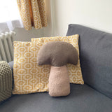 Decorative pillows on a gray sofa with a geometric patterned pillow and a mushroom-shaped pillow.