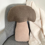 Textured mushroom-shaped pillow on a chair with a blanket draped over it