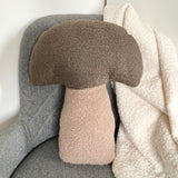 Textured mushroom-shaped pillow on a chair with a blanket draped over it