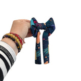 Hand holding a colorful bow with a white background
