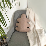 Decorative pillow shaped like a leaf on a gray couch next to a plant.