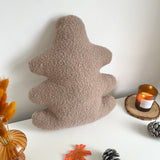 Textured beige pillow on a white surface with decorative items.