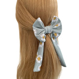 Hair bow with floral pattern tied in a ponytail on a white background