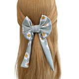 Hair bow with floral design on a person's head against a white background