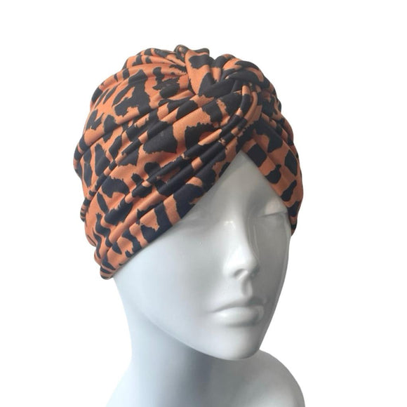 Patterned orange and black twist turban hat for women.