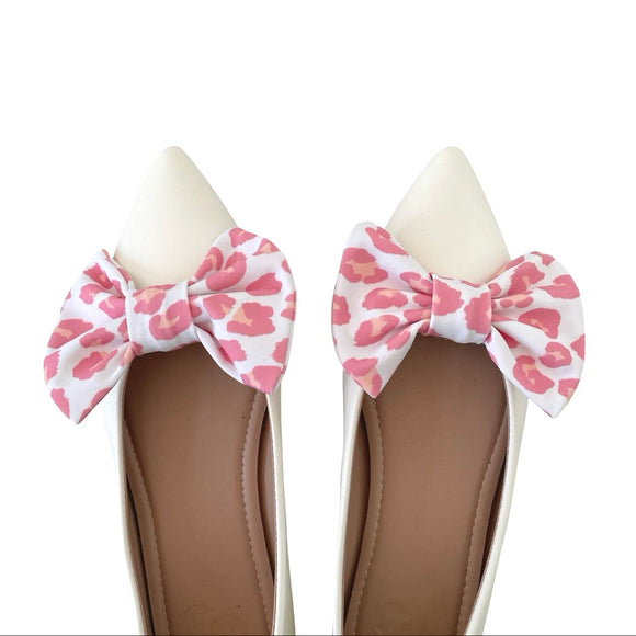 Pair of shoes with pink leopard print bows on a white background