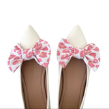 Pair of shoes with pink leopard print bows on a white background