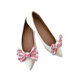White high-heeled shoes with pink bow decorations on a white background