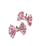 Two pink and white patterned bow clips on a white background