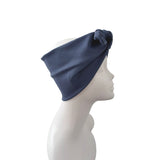 A navy blue fabric headband with a twisted knot detail on the side, displayed on a white mannequin head in profile against a plain white background.