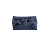 A navy blue fabric headband with a large decorative bow at the center, photographed flat against a solid white background.