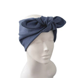 A navy blue fabric headwrap or turban hat with a large twisted bow detail, displayed on a white mannequin head against a plain white background.