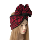 A red and black zebra-print hair wrap styled on a mannequin head with long blonde hair, set against a plain white background.