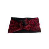 A black and red wavy patterned headband with a central knotted bow detail, displayed flat against a solid white background.