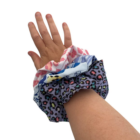 Hand wearing a colorful scrunchie on a white background