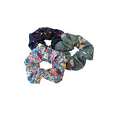 Three colorful scrunchies with floral and animal prints on a white background