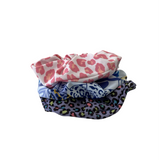Three fabric scrunchies with leopard print pattern on a white background