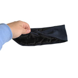 A hand wearing a light blue ribbed sleeve is holding a black satin headband against a plain white background.