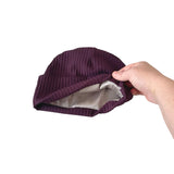 Purple beanie held by a hand on a white background