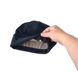 Navy blue shower cap held by a hand on a white background