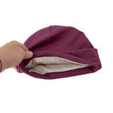 Purple fabric  cap being held with a beige interior on a white background