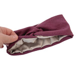 Purple headband with a satin bow held by a hand on a white background