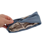 Hand holding a blue headband with beige interior on a white background