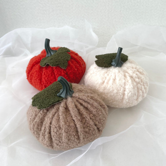 Three boucle pumpkins in rust, white, and beige on a white background
