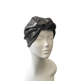 Black turban on a mannequin head against a white background