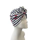 Navy and white striped headscarf with red cherries on a mannequin head against a white background