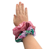 Hand wearing a pink scrunchie with floral pattern on a white background ireland