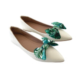 White flats with green leaf decorations on a white background