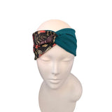 A teal and floral knotted headband displayed on a white mannequin head against a plain white background.