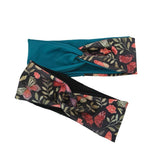 A twisted knot headband featuring a dark navy floral and butterfly pattern on one side and a solid teal blue fabric on the other, shown on a plain white background.