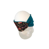 A fabric eye mask headband with a teal blue twisted back and a black floral print front, displayed on a white mannequin head against a white background.