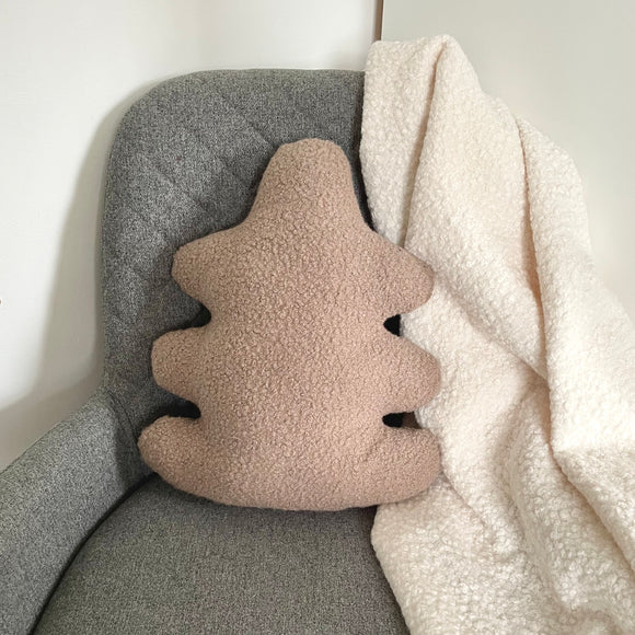 Oak leaf-shaped pillow with textured surface on a gray chair next to a white blanket