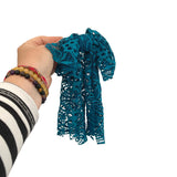 Hand holding a blue lace scarf against a white background