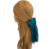 Mannequin head with brown hair and a blue lace scrunchie on a white background