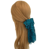 Mannequin head with brown hair tied with a blue lace scrunchie on a white background