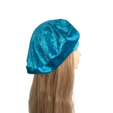 Blue velvet bonnet on a mannequin head with long hair against a white background