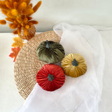 Decorative decor in green, red, and gold on a white surface with a straw hat and dried flowers.