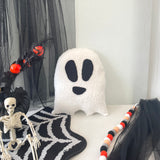 Halloween-themed decor with a ghost pillow, skeleton, and spider web on a white background.